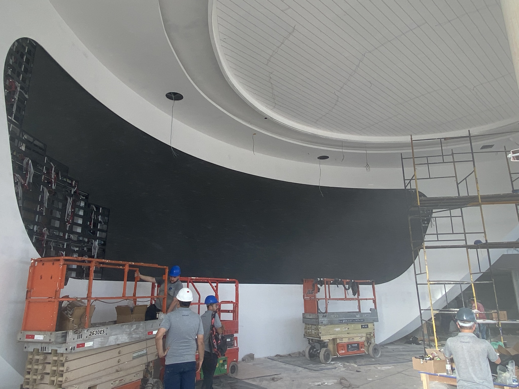 Painel de LED curvo com módulos instalados, embutido na parede branca do showroom da Denza