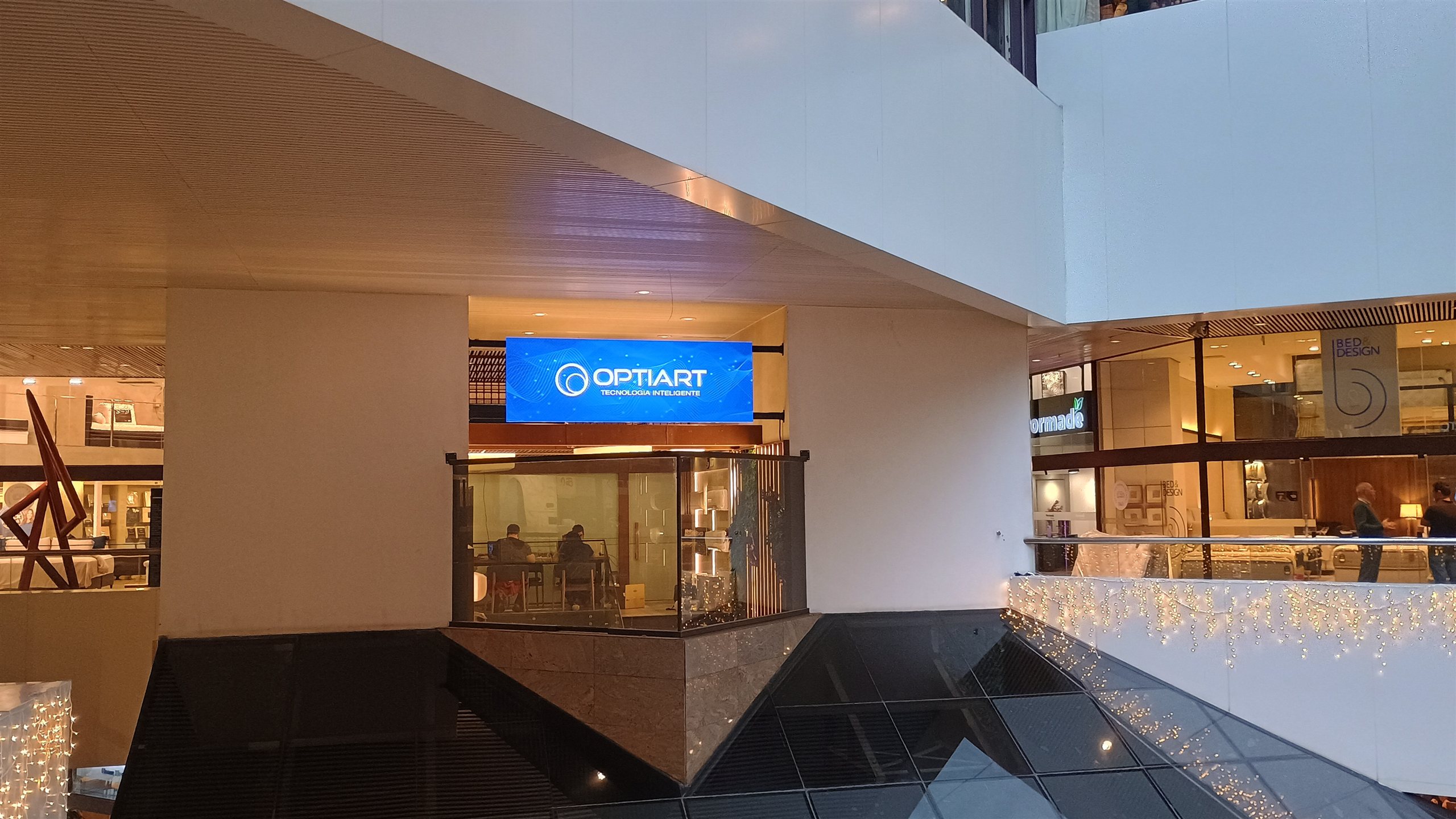Painel de LED panoramico exibindo a marca acima da vitrine de uma loja em shopping