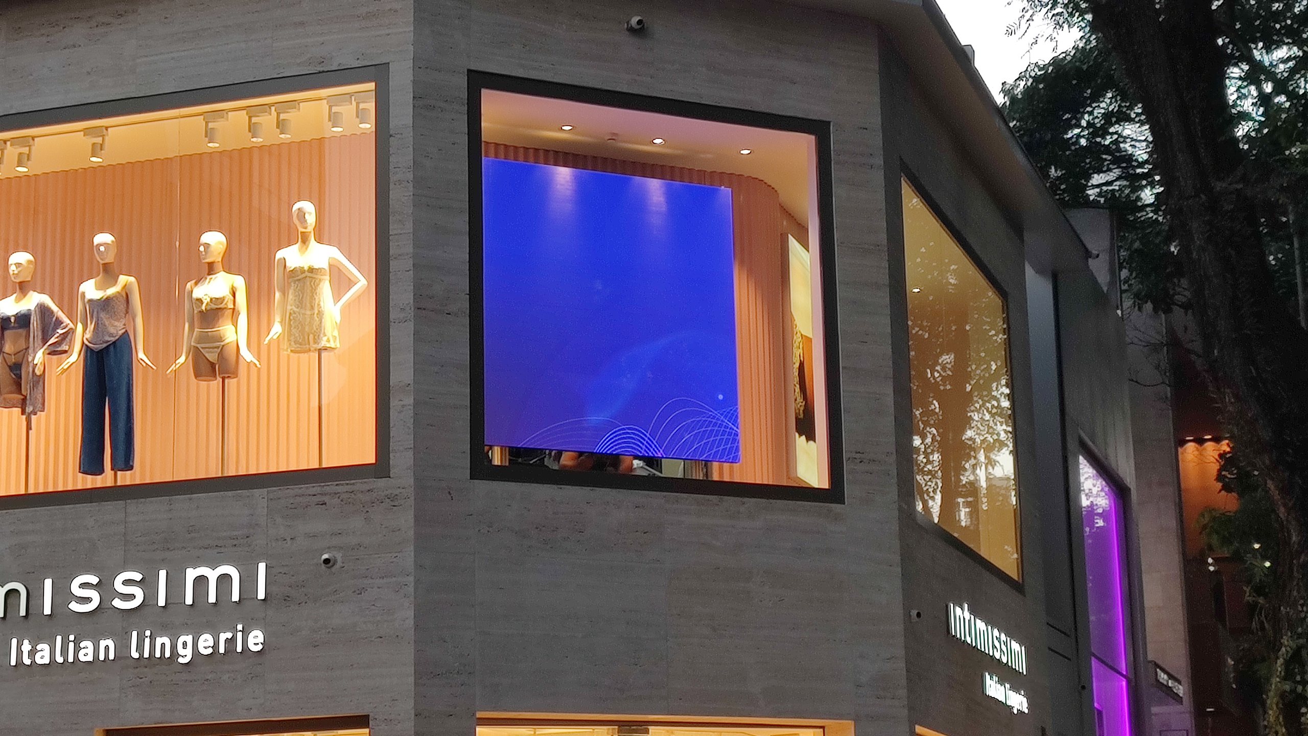Painel de LED exibindo conteudo dinamico na vitrine da loja Intimissimi Oscar Freire, ao lado dos manequins