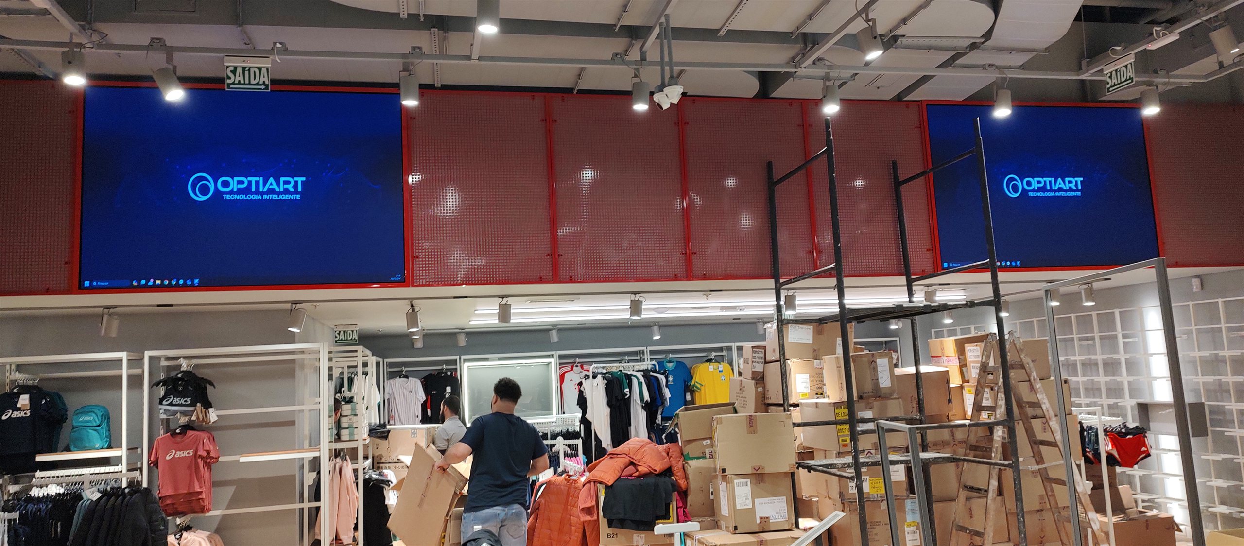 Vista do interior da loja Centauro com dois paineis de LED da Optiart acesos na testeira, sobre a area de vendas