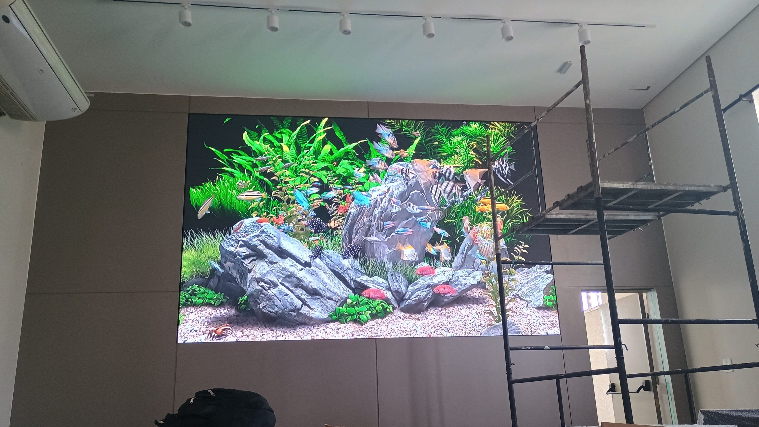 Painel de LED indoor exibindo imagem colorida de aquário em alta resolução durante a instalação