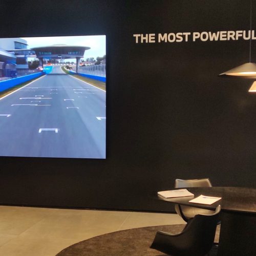 Painel de LED P2.5 instalado na concessionaria BMW Grand Brasil, exibindo conteudo da BMW M em um circuito de corrida, ao lado de lounge de atendimento