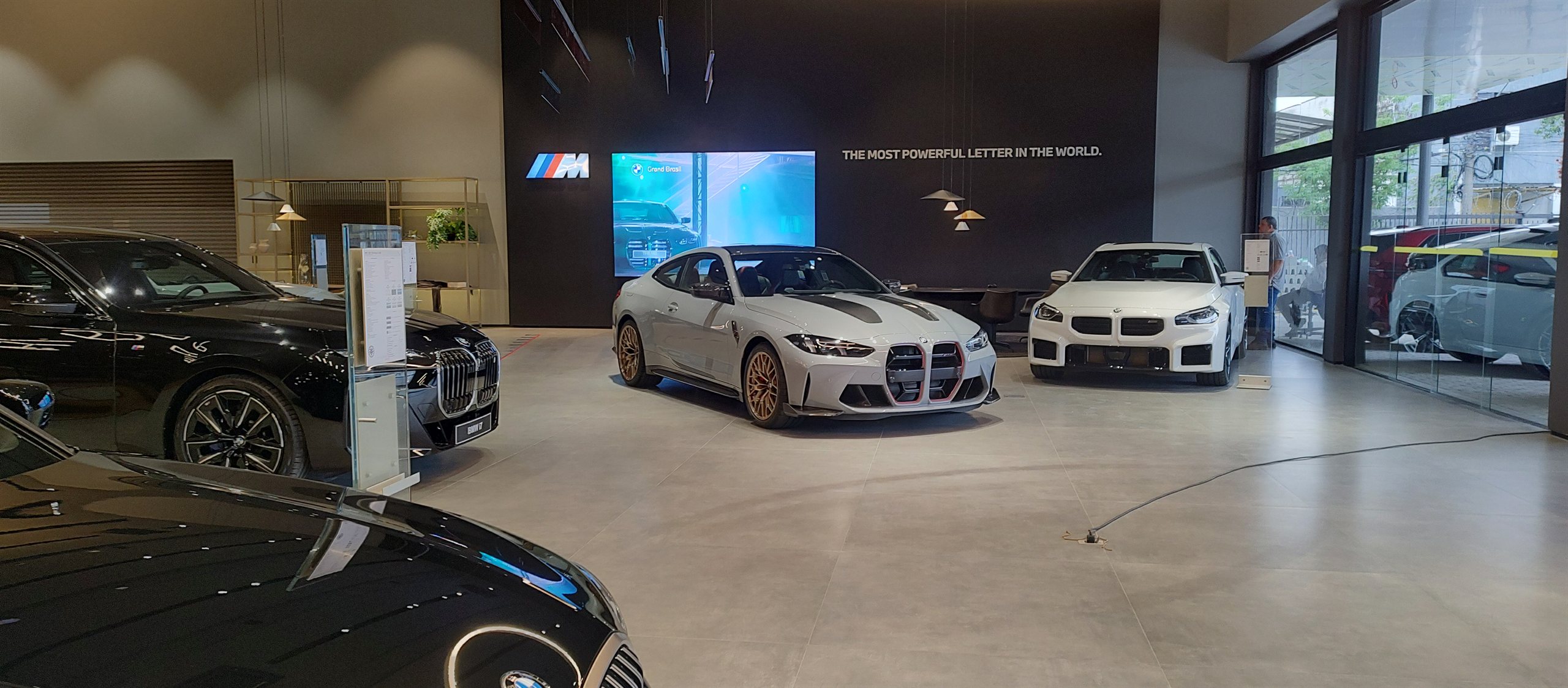 Showroom da concessionaria BMW Grand Brasil com modelos BMW M e o painel de LED P2.5 ligado ao fundo valorizando o ambiente