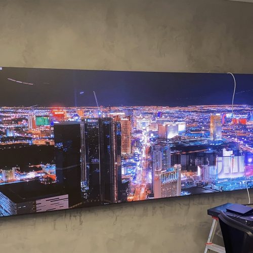 Painel de LED indoor exibindo imagem panoramica noturna de cidade em ambiente corporativo de empresa de tecnologia