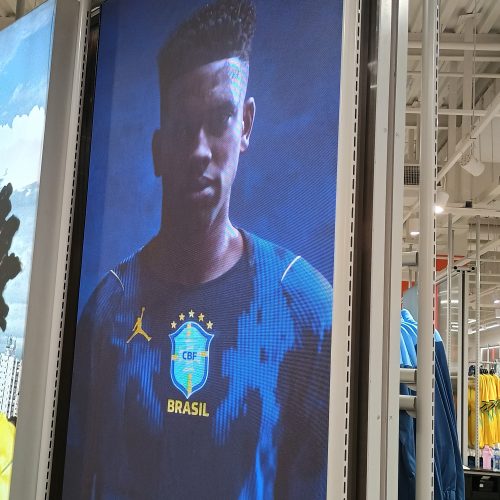 Painel de LED instalado em gôndola de loja exibindo campanha da seleção brasileira de futebol