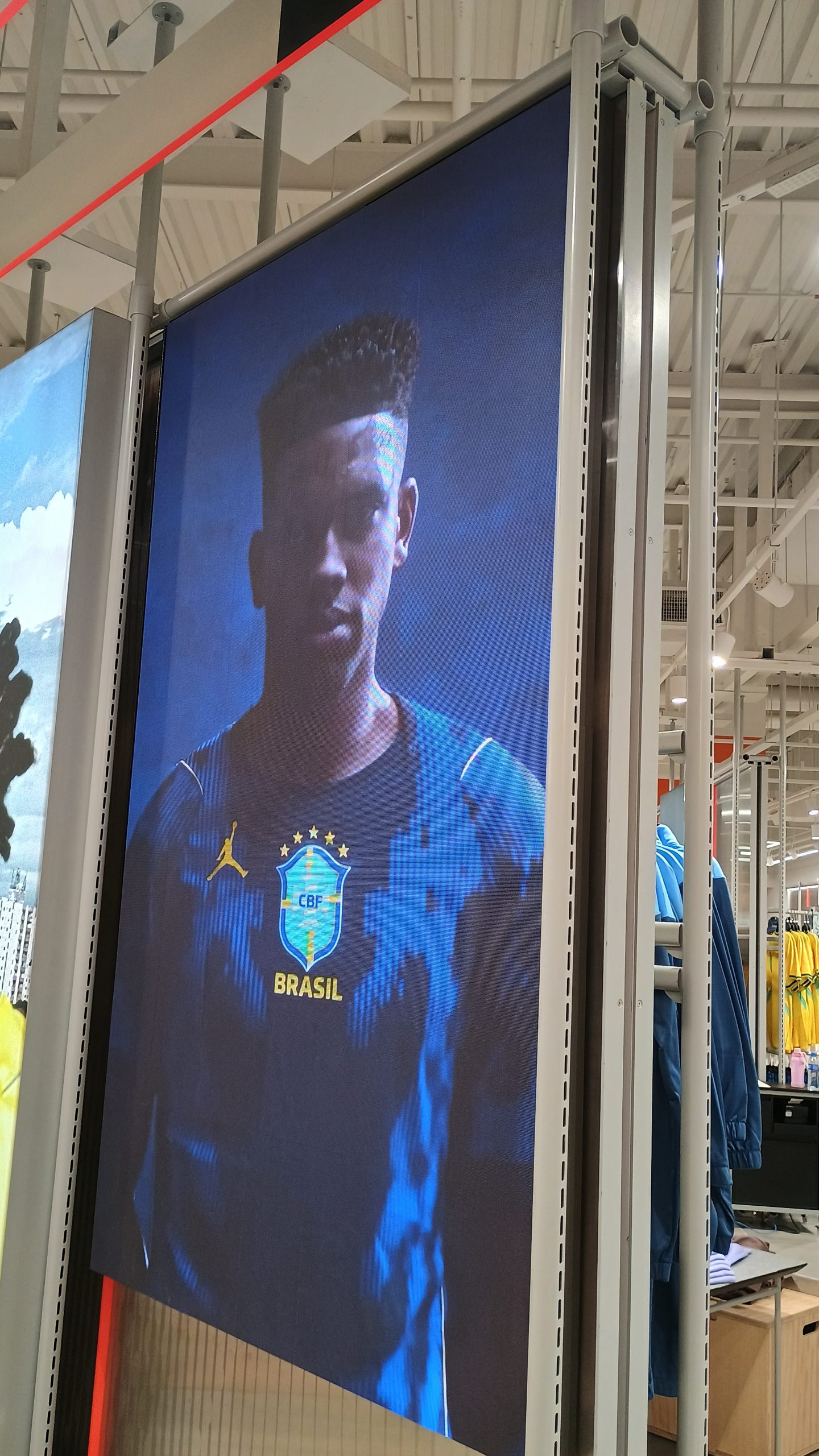 Painel de LED instalado em gôndola de loja exibindo campanha da seleção brasileira de futebol