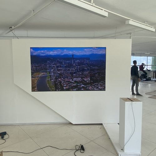 Painel de LED embutido em parede expositiva exibindo vista aérea de cidade em alta resolução