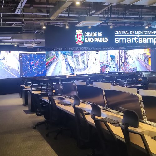 Sala de monitoramento com painel de LED panorâmico exibindo mapa e imagens de câmeras urbanas
