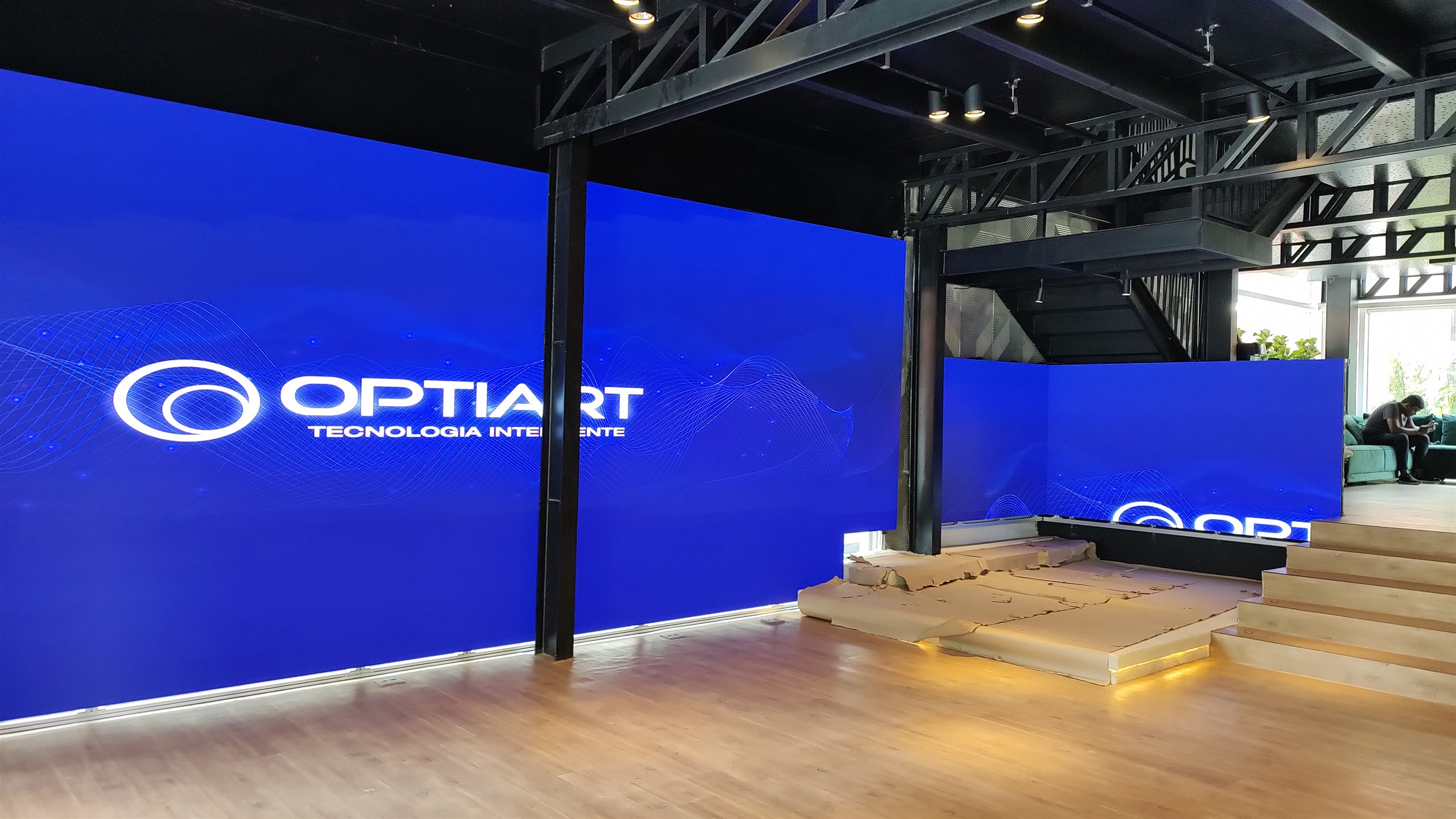 Painéis de LED ligados exibindo a logomarca da Optiart no ambiente do showroom Yamaha Intermezzo