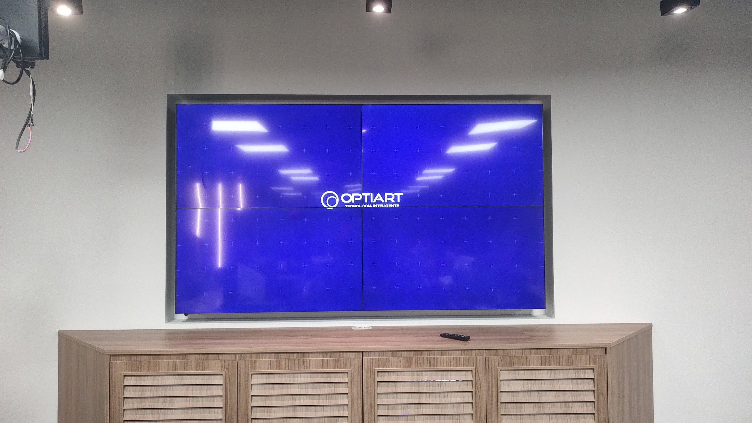 VideoWall 2x2 ligado sobre móvel de madeira no escritório da Prudential em Botafogo, Rio de Janeiro
