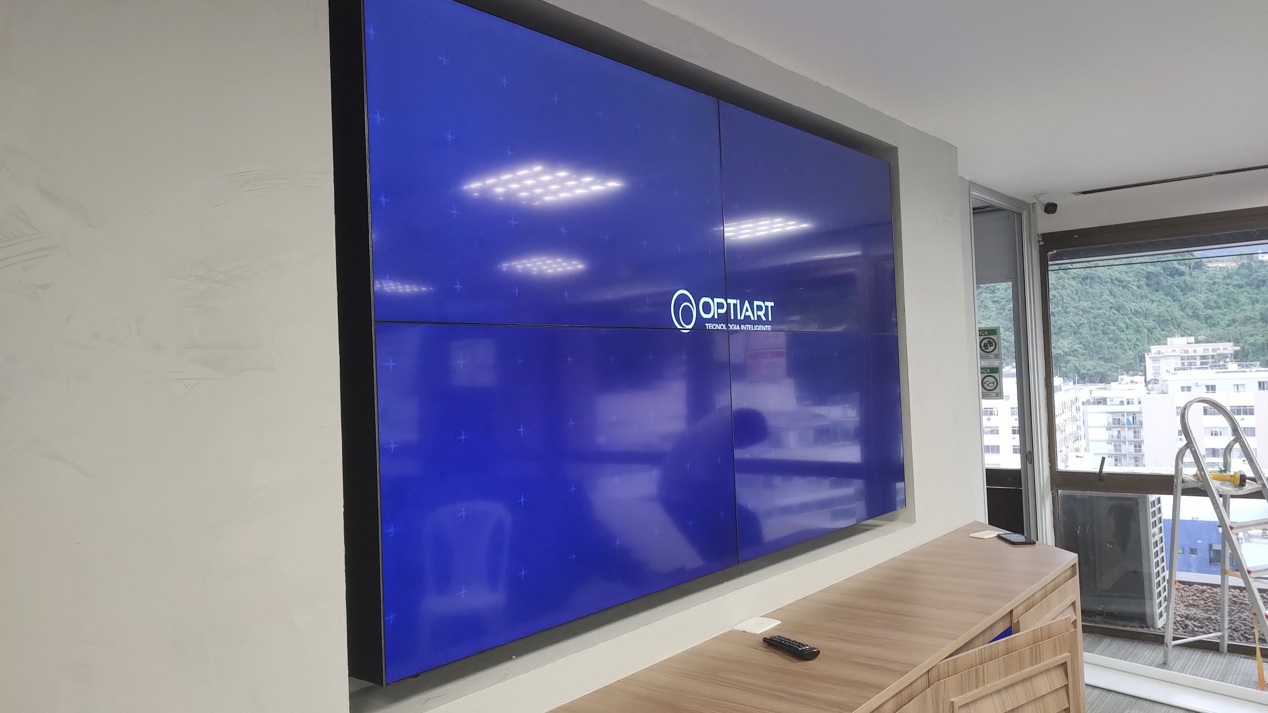 VideoWall 2x2 da agência Black Belt visto em ângulo, com janela e vista do Rio de Janeiro ao lado
