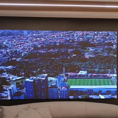 Painel de LED na recepcao do centro de treinamento do Red Bull Bragantino exibindo imagem aerea do estadio