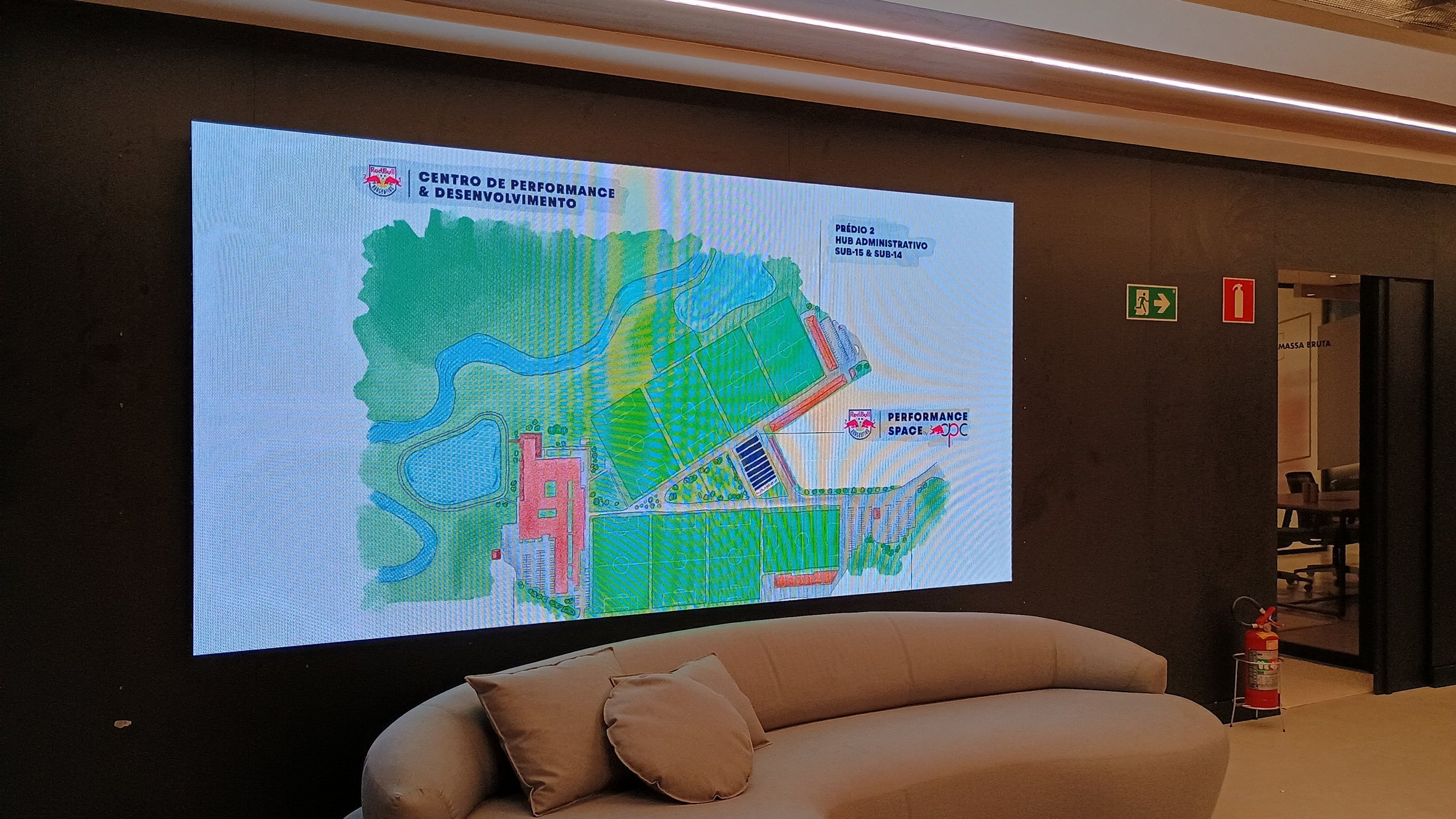 Painel de LED da recepcao exibindo o mapa do Centro de Performance e Desenvolvimento do Red Bull Bragantino