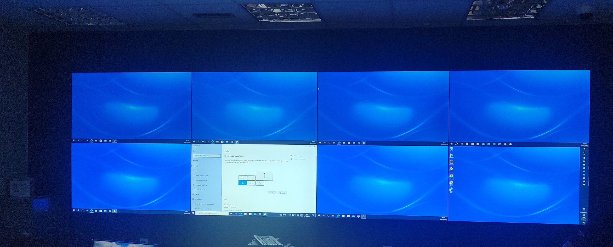 VideoWall 2x4 com oito monitores de 55 polegadas instalado na sala de controle de um data center, ocupando a largura da parede frontal
