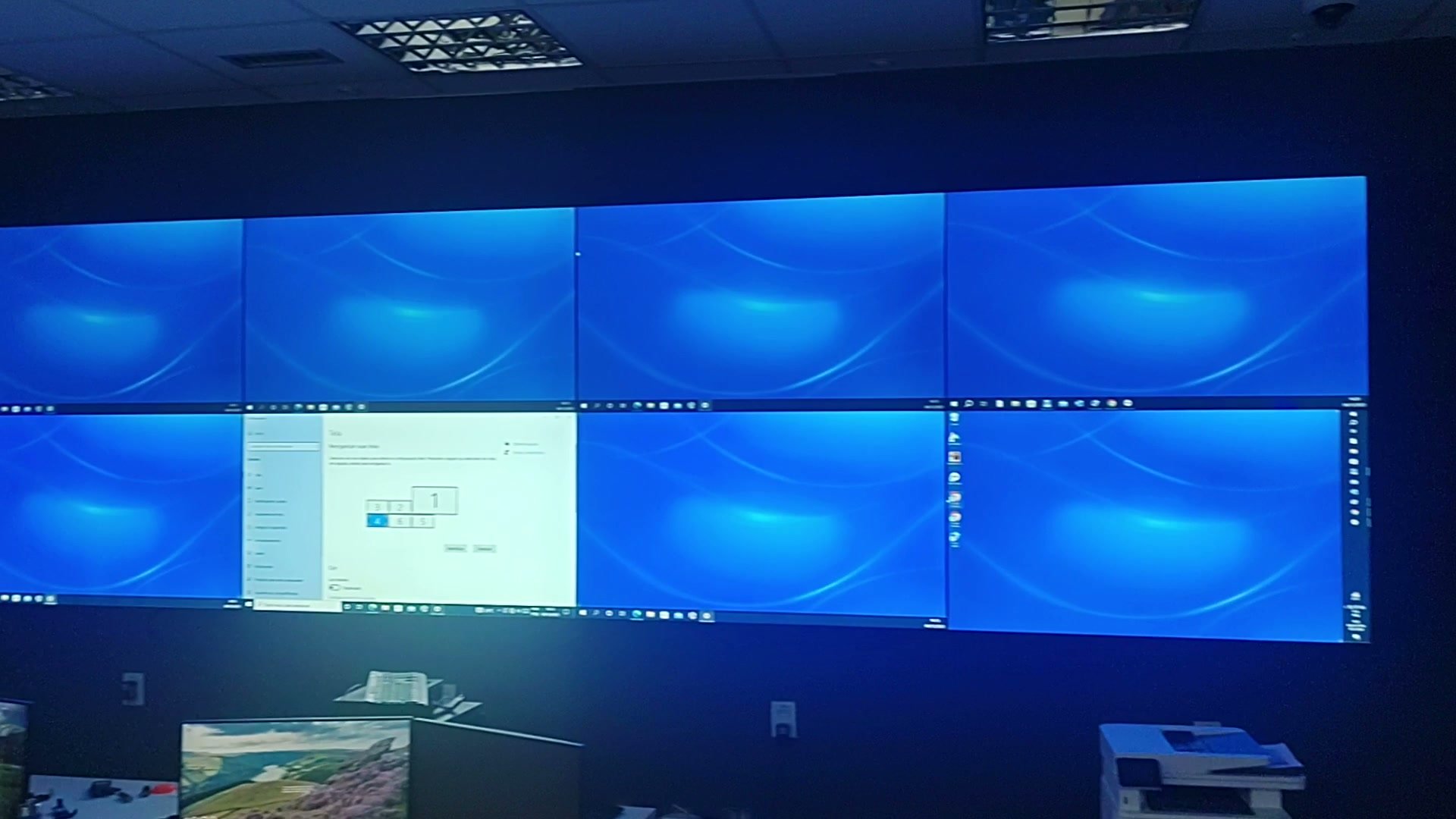 Vista ampla do videowall 2x4 ligado na sala de controle do data center, com as quatro colunas e as duas linhas de monitores alinhadas