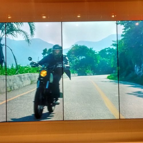 VideoWall 1x4 vertical na Foxton Rio Design Barra exibindo vídeo de motociclista em tela cheia