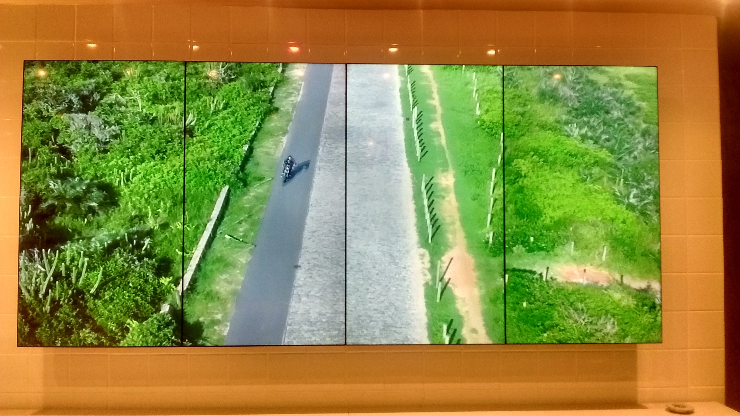 VideoWall 1x4 vertical exibindo imagem aérea de estrada e vegetação na loja Foxton Rio Design Barra