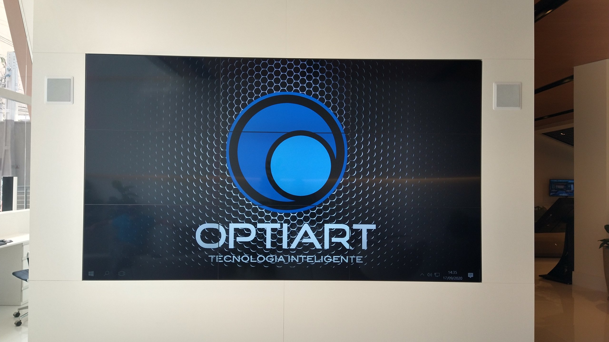 Vista frontal do VideoWall 3x3 embutido em nicho, com as nove telas ligadas formando uma única imagem contínua