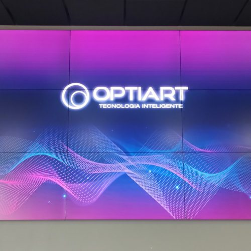 Vista frontal de VideoWall 3x3 com nove monitores de 55 polegadas exibindo conteúdo contínuo em ambiente corporativo