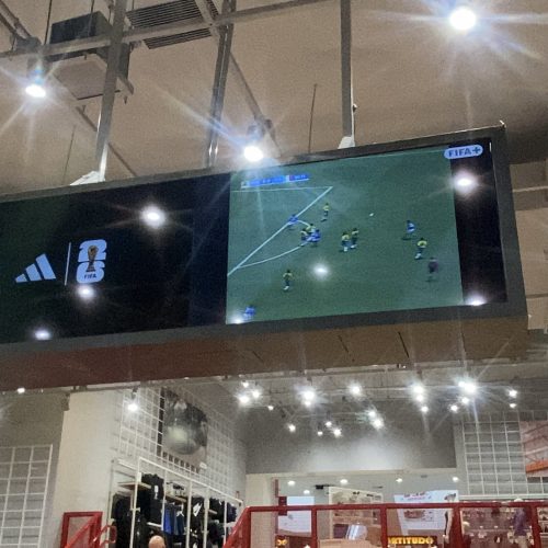 VideoWall suspenso exibindo conteúdo esportivo e transmissão de futebol na loja Centauro de Itaquera