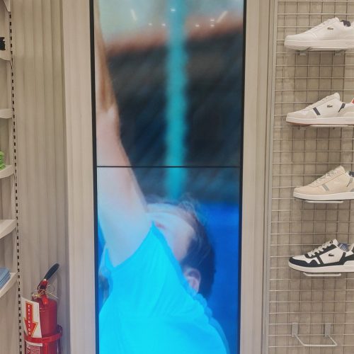 VideoWall vertical com dois monitores LG 49 polegadas empilhados exibindo campanha em loja Lacoste em Florianópolis