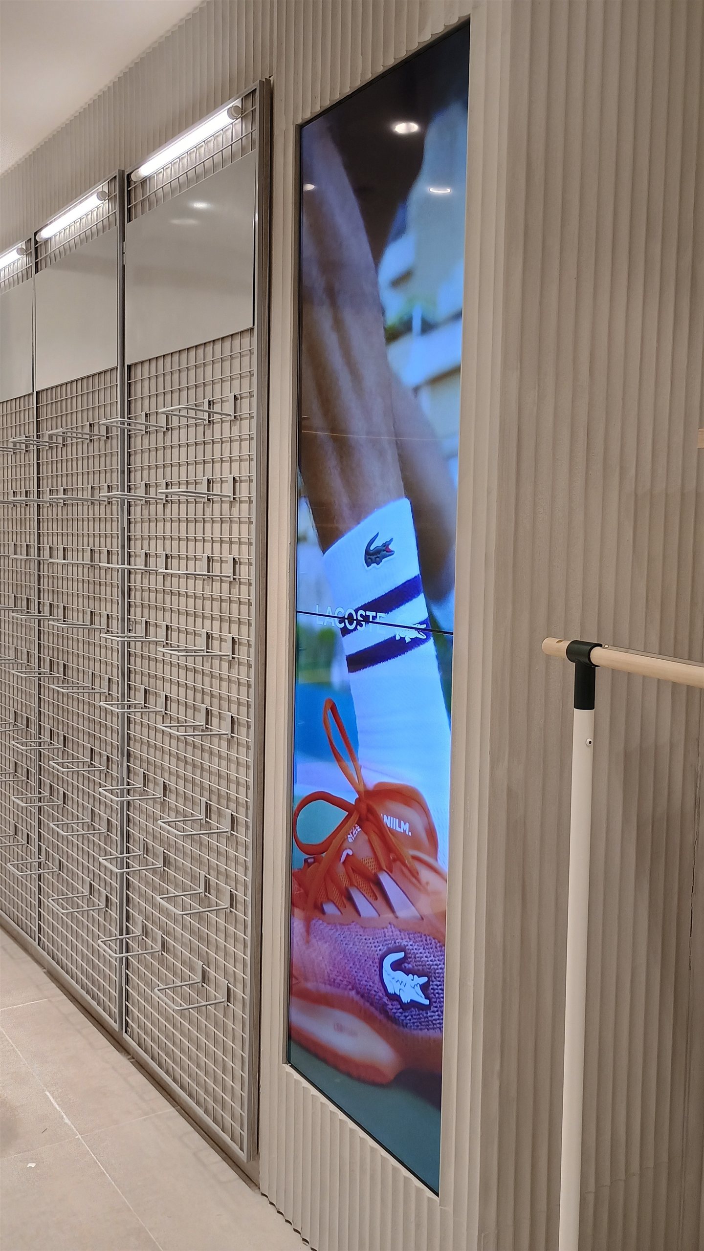 VideoWall vertical com dois monitores LG 49 polegadas exibindo campanha de tênis em loja Lacoste em Londrina